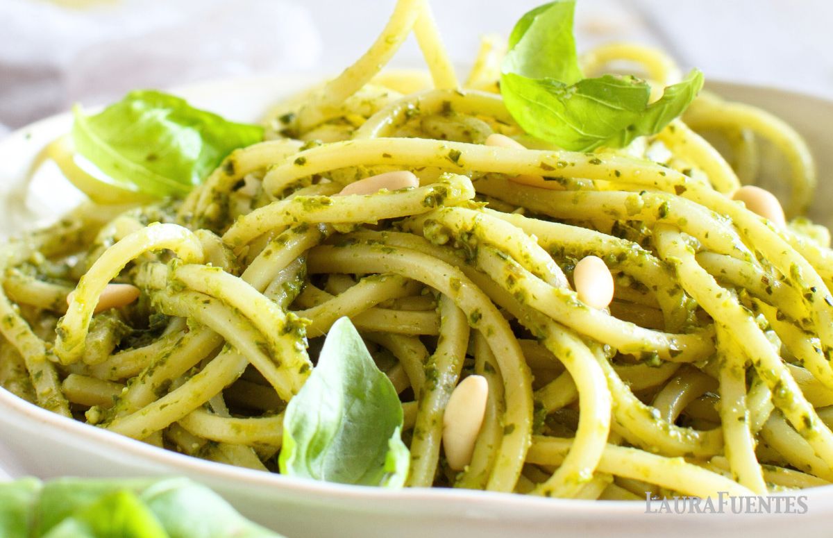 un plato de espaguetis al pesto con unas hojas de albahaca
