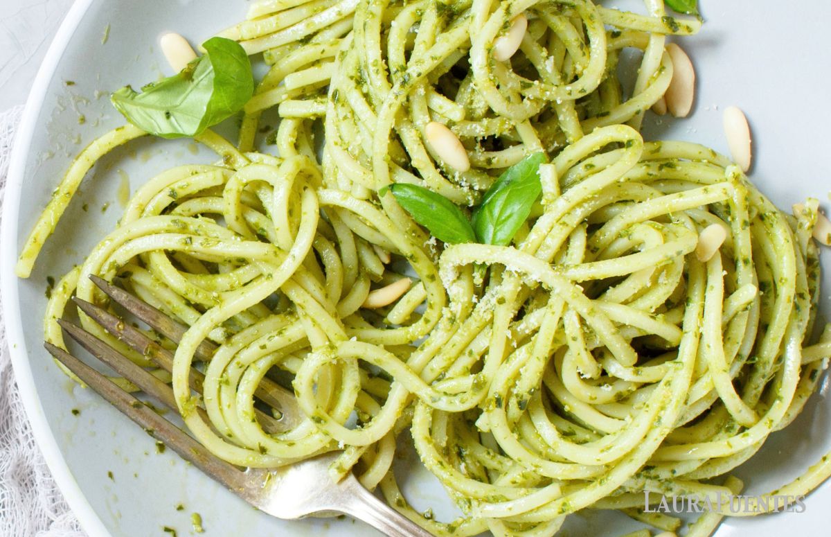 vista superior de un plato de espaguetis al pesto con unas hojas de albahaca