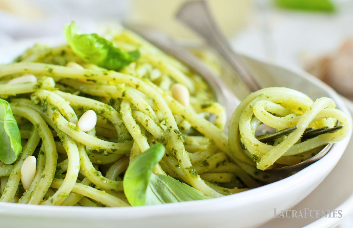 un plato de espaguetis al pesto con unas hojas de albahaca