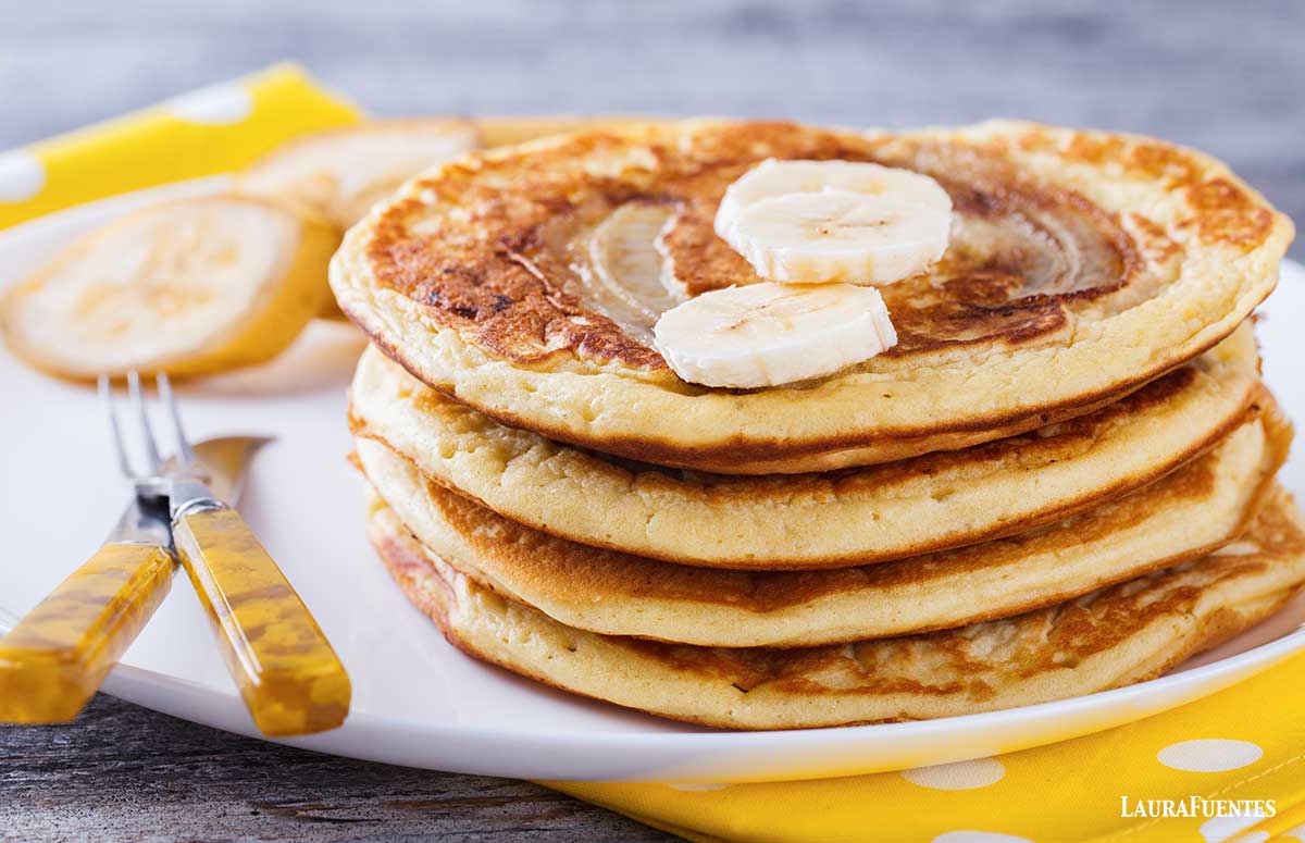 una pila de tortitas de plátano en un plato con cubiertos