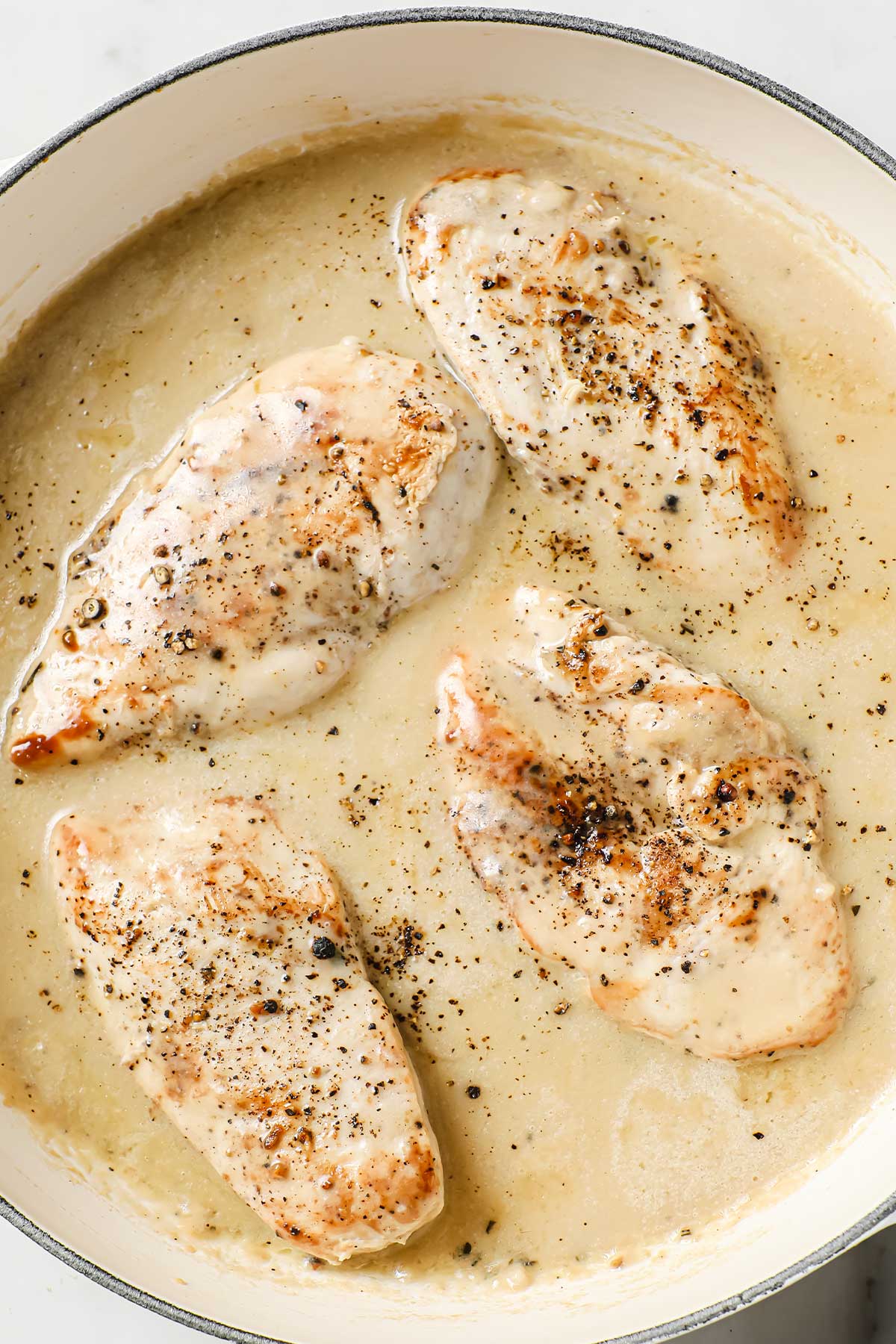 vista cenital de una sartén con pechugas de pollo con salsa