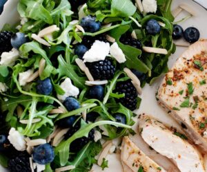 un plato de pollo con ensalada de espinacas, arándanos y queso