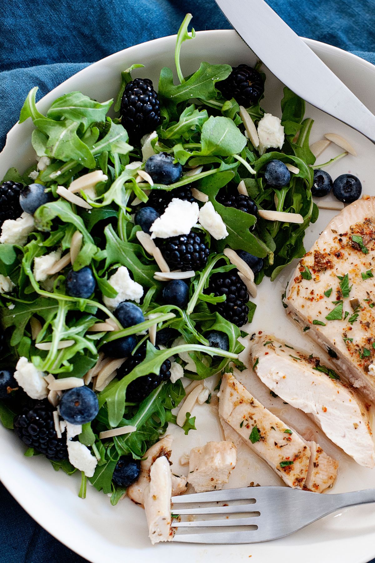 un plato de pollo con ensalada de espinacas, arándanos y queso
