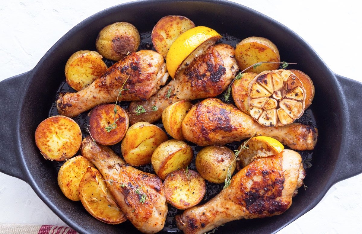 vista cenital de muslos de pollo con patatas al horno en una fuente