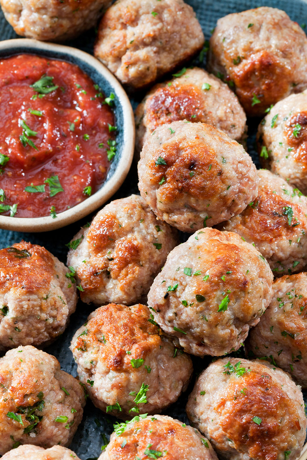primer plano de albóndigas de pollo junto a un recipiente con salsa de tomate