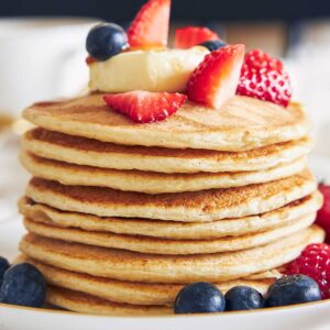 una pila de tortitas de queso cottage con frutos rojos por encima