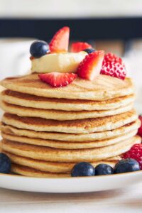 una pila de tortitas de queso cottage con frutos rojos por encima