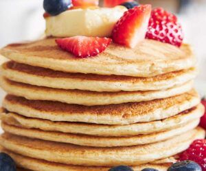 una pila de tortitas de queso cottage con frutos rojos por encima