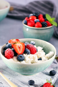 bol con queso cottage y frutas y otro bol más pequeño detrás con bayas
