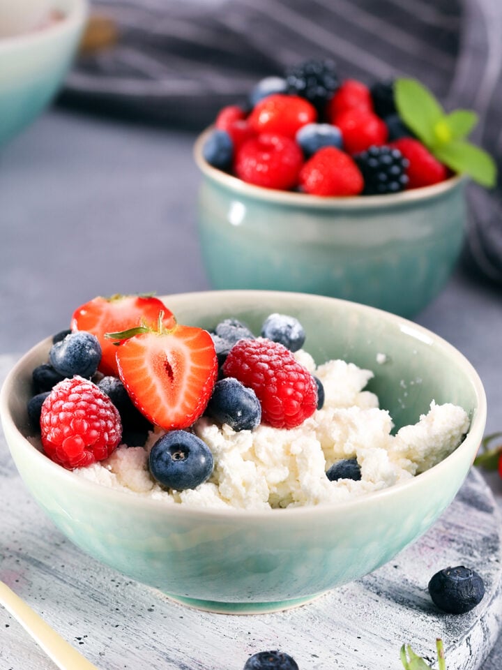 bol con queso cottage y frutas y otro bol más pequeño detrás con bayas